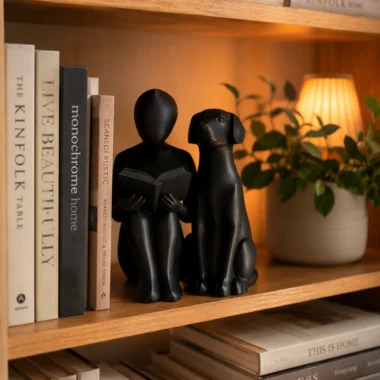 Black abstract reading and dog statue on bookshelf with books and warm lamp glow