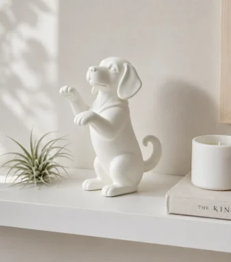 White raised paw puppy figurine on minimalist Scandi shelf with air plant and candle
